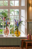 Runde Gartentischszene mit rotem Mosaiktisch Vase mit Blumen Glas und Teller mit Trauben und Macaron saisonale Wohnaccessoires